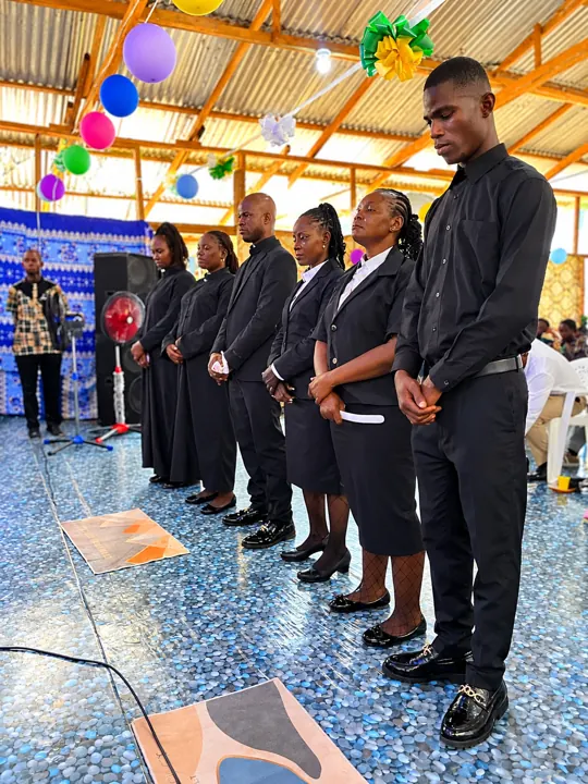 Ordinands in black standing in prayer